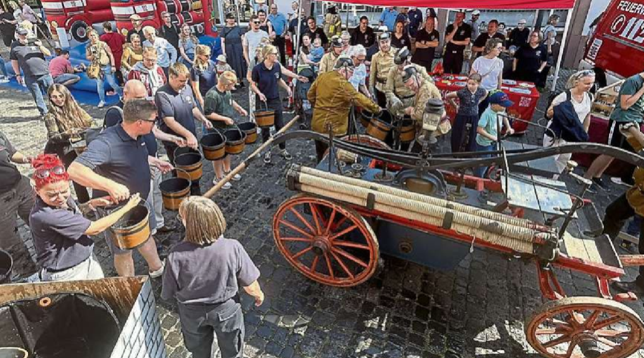 Bei der historischen Löschübung werden sogar Touristen eingespannt, um von der alten Handpumpenspritze aus eine Eimerkette zu bilden. Fotos: Klaus-Dieter Häring